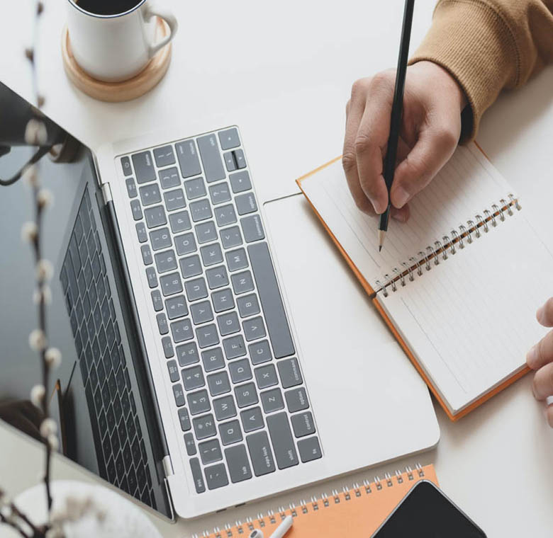 dettaglio mani su quaderno e computer portatile, donna che studia